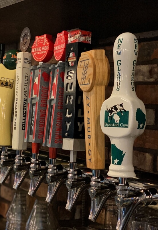 row of beer taps at river falls brewery featuring spotted cow and surly