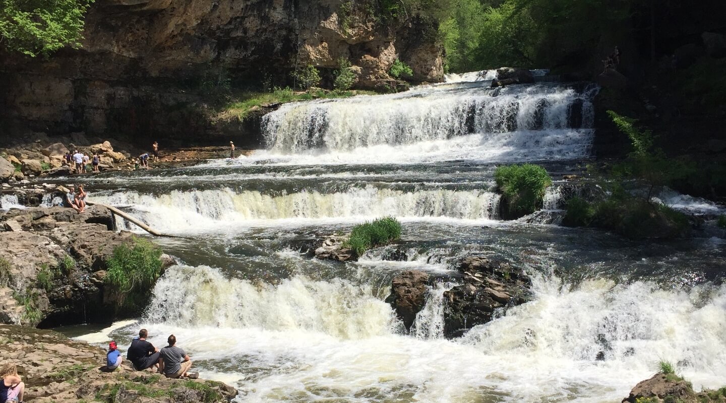 scenic waterfall at willow river state park with people exploring rocks and water