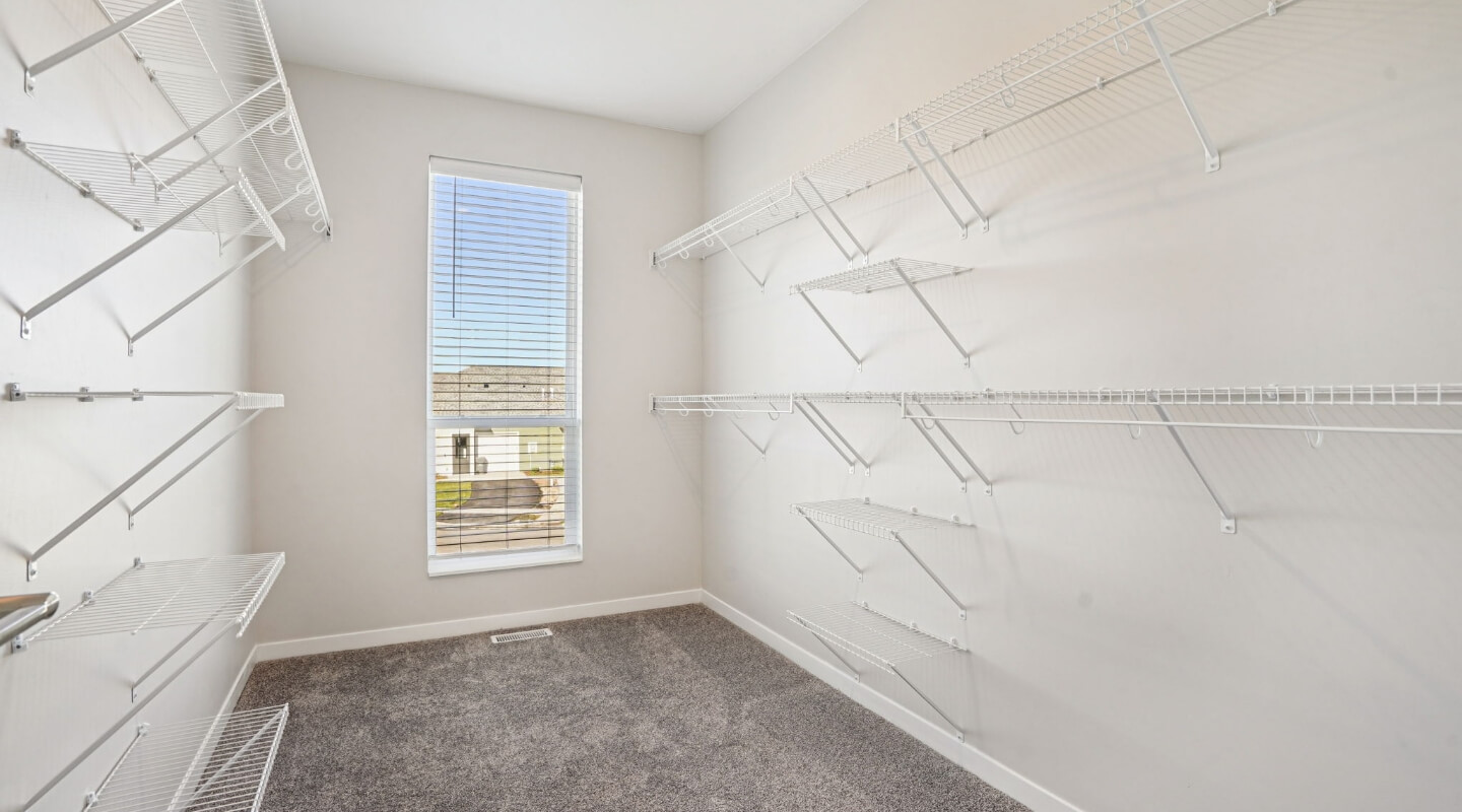 Walk-in closet with white wire shelving and natural light from a large window.