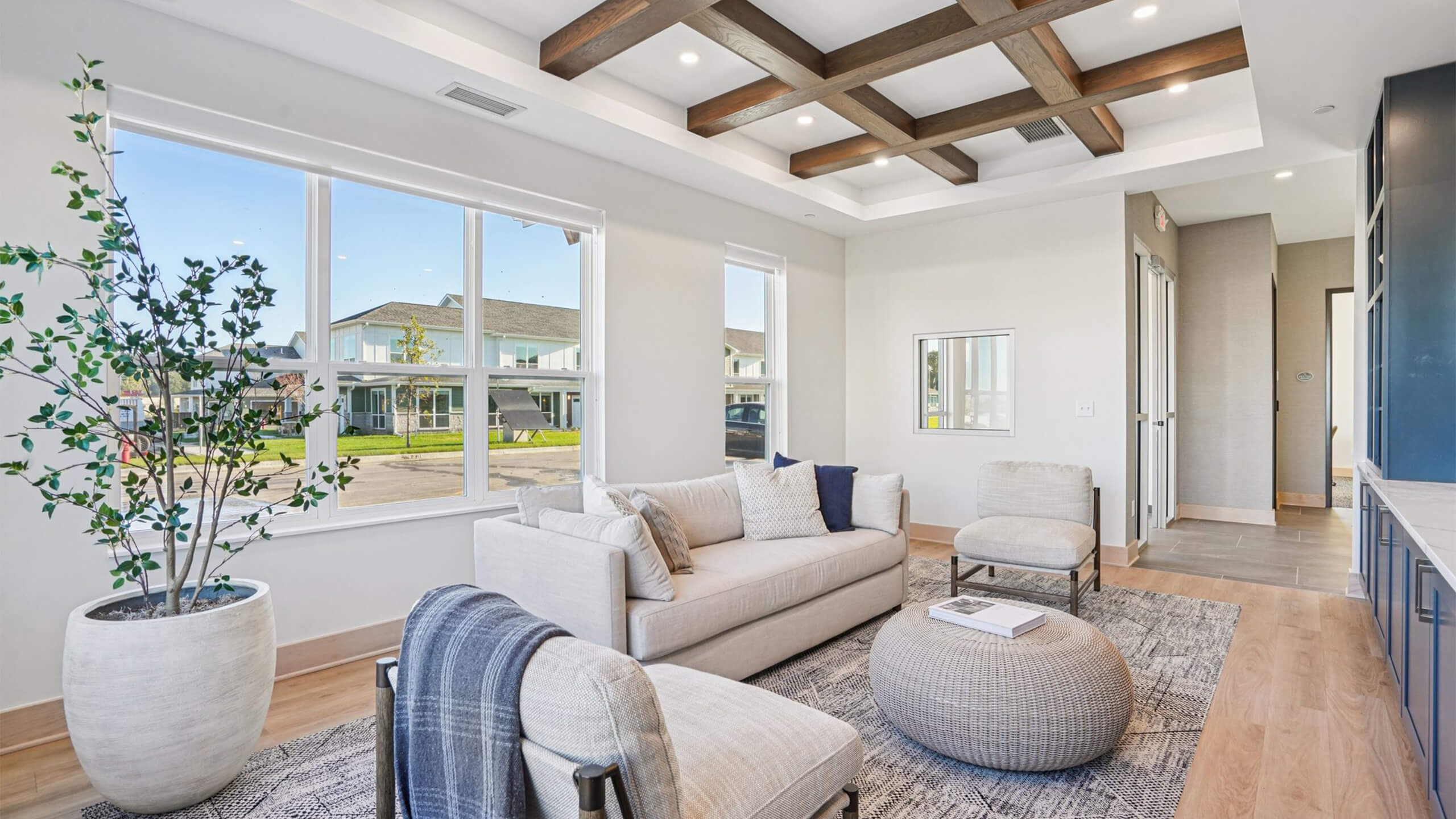 Cozy clubhouse lounge with modern furniture, wood ceiling beams, and large windows overlooking the community.